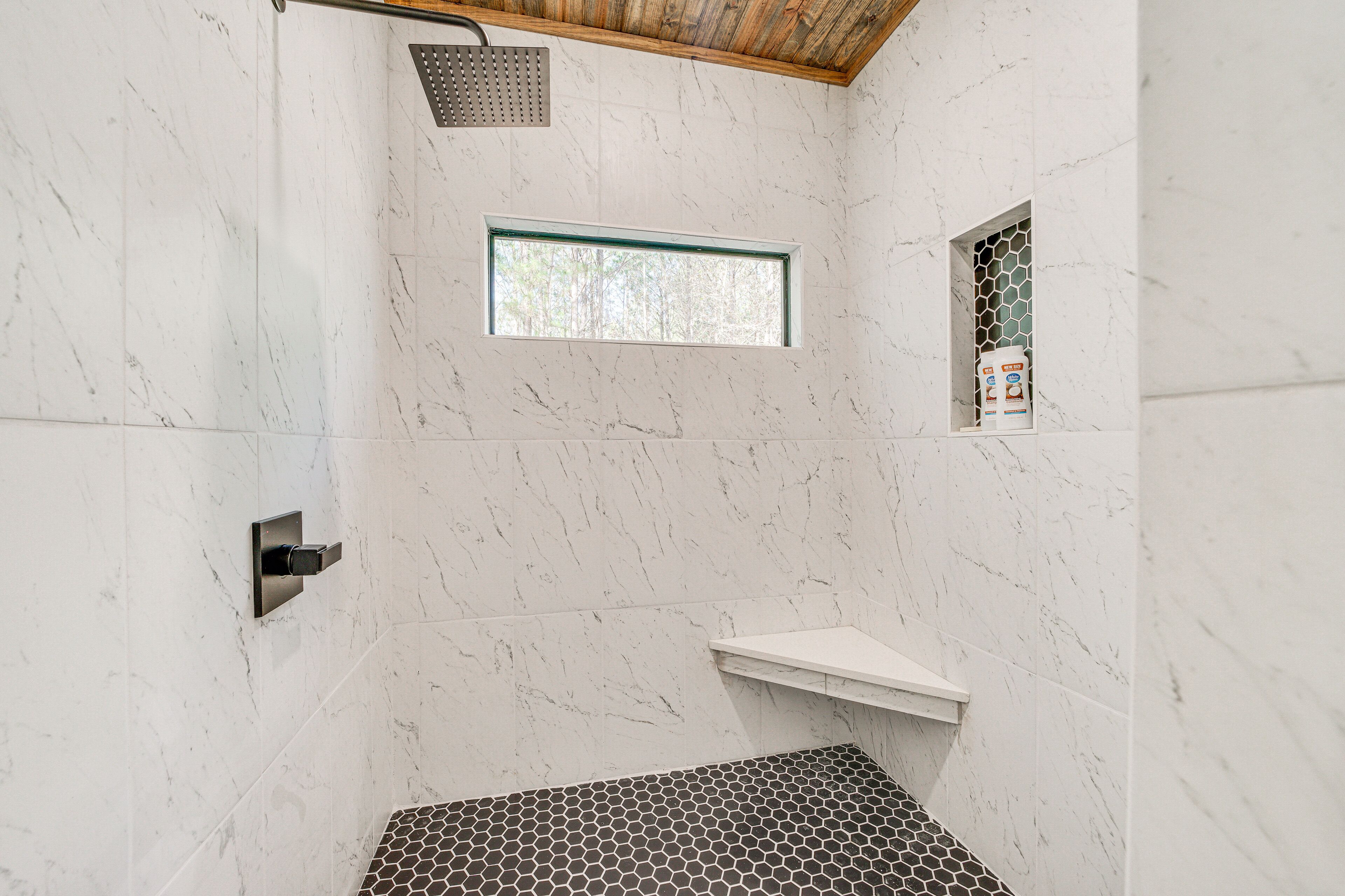 A modern shower with a rain showerhead, a small window, and a shelf.