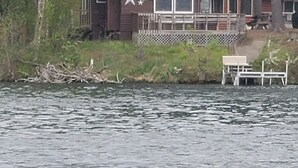 Une cabane avec un toit végétalisé, une terrasse et un petit quai.