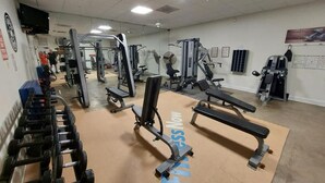A gym with various exercise equipment, including dumbbells, benches, and weight machines.