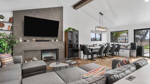 Un salon moderne doté d’un téléviseur à écran plat, d’une cheminée et d’un coin repas avec une table et des chaises.
