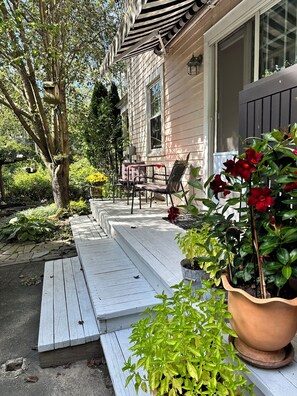 A wooden deck with outdoor seating, a potted plant, and a house with a window and door. - Steps from the Hudson River- 
Cozy & Comfy sums up this 3 Bedroom 2 Bath home. (Sparkill)