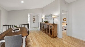 A dining area with a wooden table and chairs, a cabinet with glass doors, and a bed in the background. - Lakeside Retreat- 7beds/4bd/2ba! Family and pet friendly!  (Zimmerman)