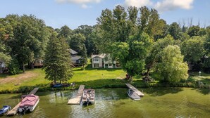 A riverside property with docked boats, a house surrounded by lush greenery, and a well-maintained lawn. - Lakeside Retreat- 7beds/4bd/2ba! Family and pet friendly!  (Zimmerman)