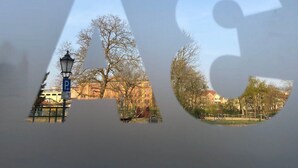 Blick durch ein Fenster, in dem die Buchstaben „AC“ zu sehen sind.