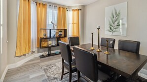 Comedor con mesa de madera oscura, sillas negras y ventilador de techo.