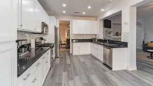Una cocina moderna con armarios blancos, una encimera negra y un lavavajillas de acero inoxidable.