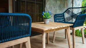 Una mesa de madera con dos sillas tejidas y una planta en maceta.