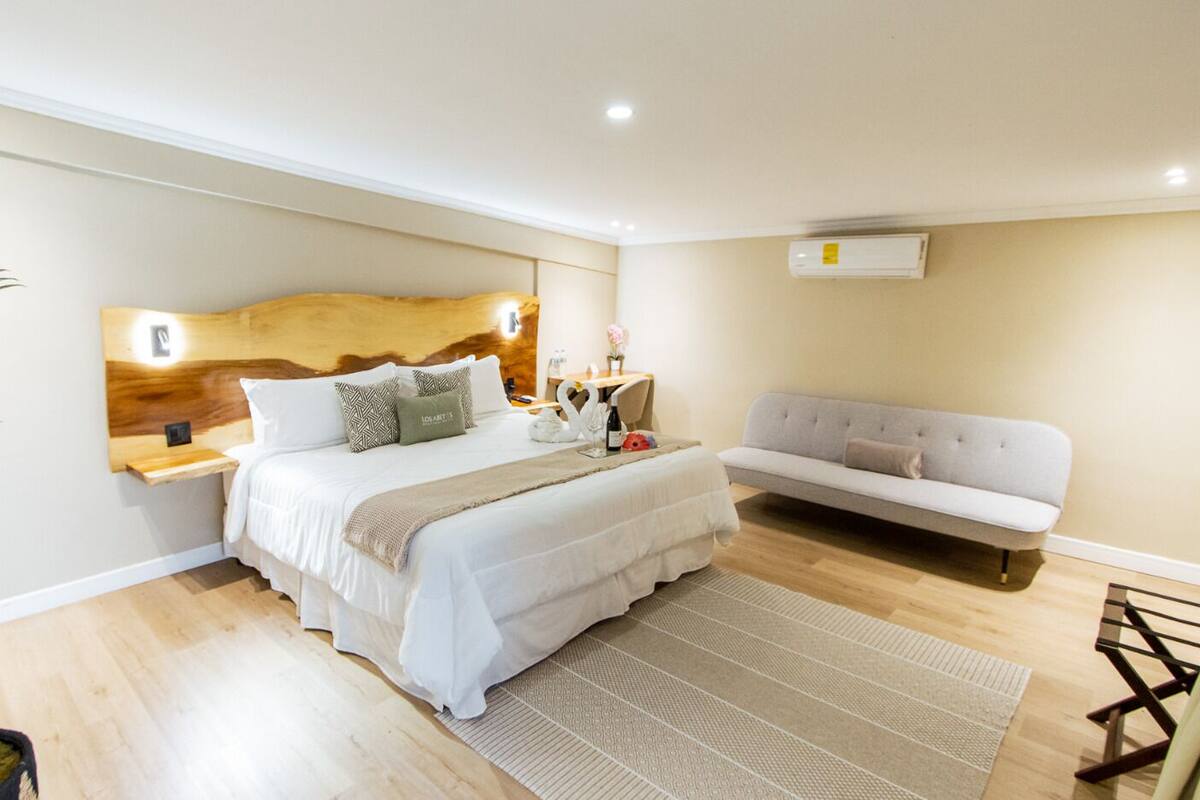 Une chambre à coucher moderne avec un grand lit, un canapé et une tête de lit en bois.