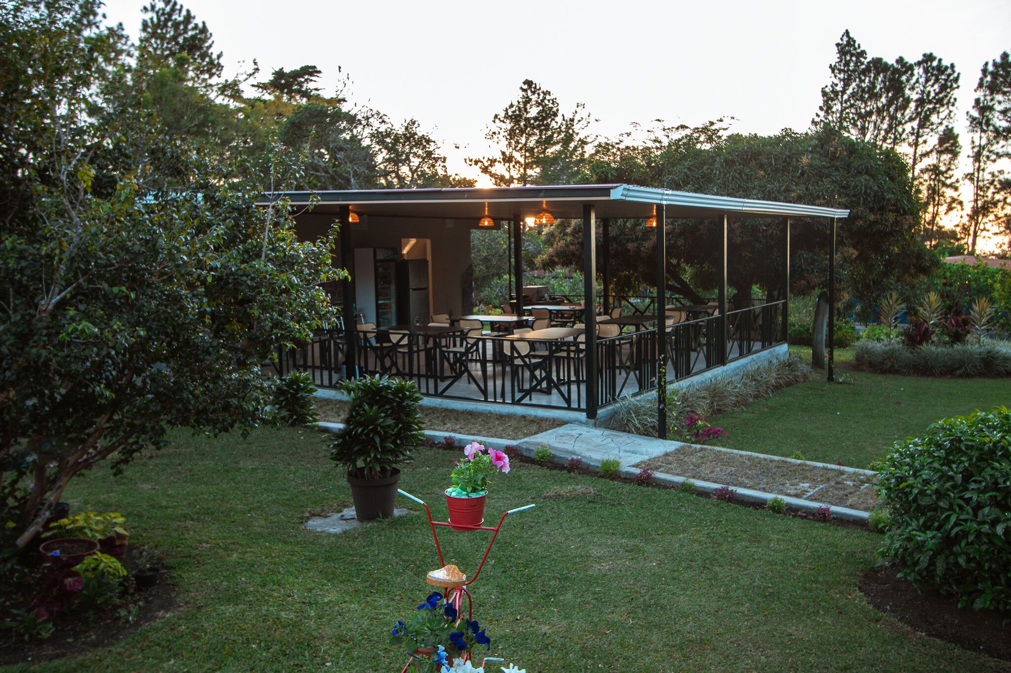 A covered outdoor patio with seating and a garden area.