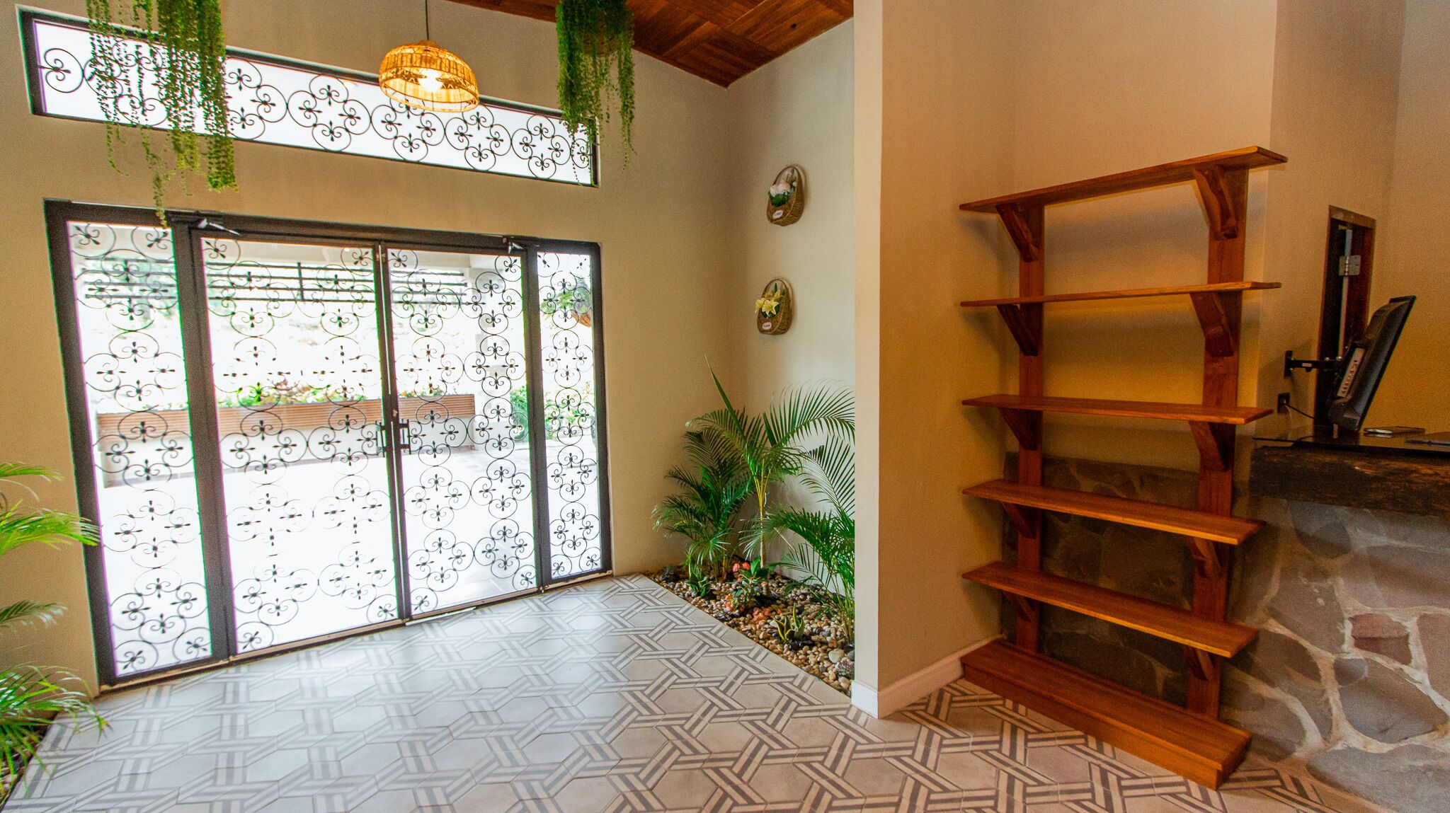 A room with a patterned floor, a wooden bookshelf, a stone fireplace, and a sliding glass door with decorative metalwork.