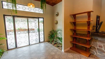A room with a patterned floor, a wooden bookshelf, a stone fireplace, and a sliding glass door with decorative metalwork.