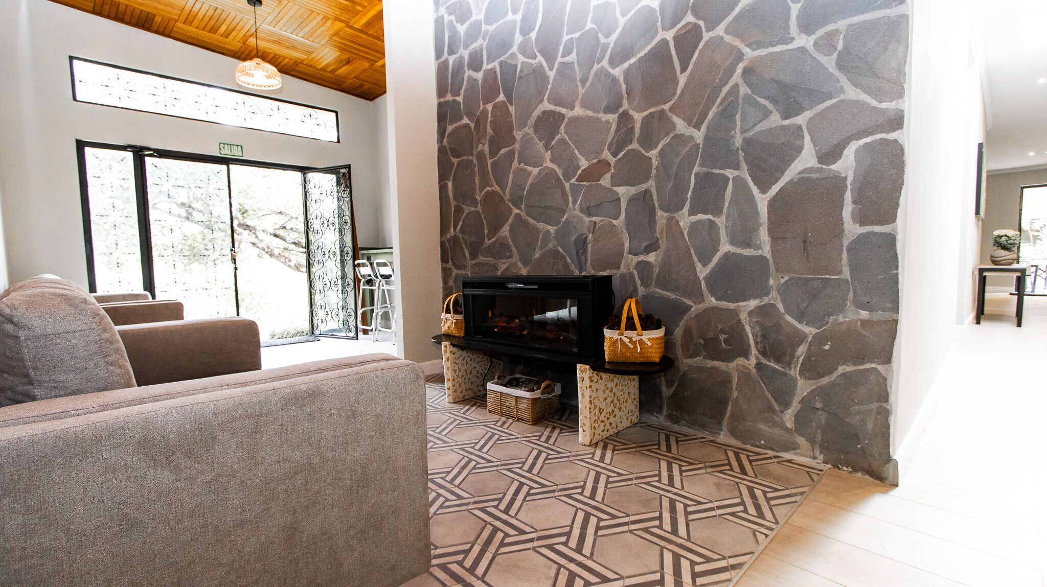 Una sala de estar con pared de piedra, chimenea, sofá y televisor.