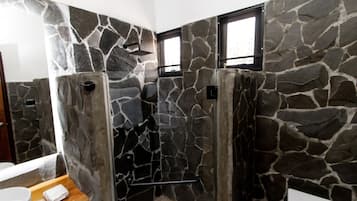 Un baño con paredes de piedra, cabina de ducha y ventana.