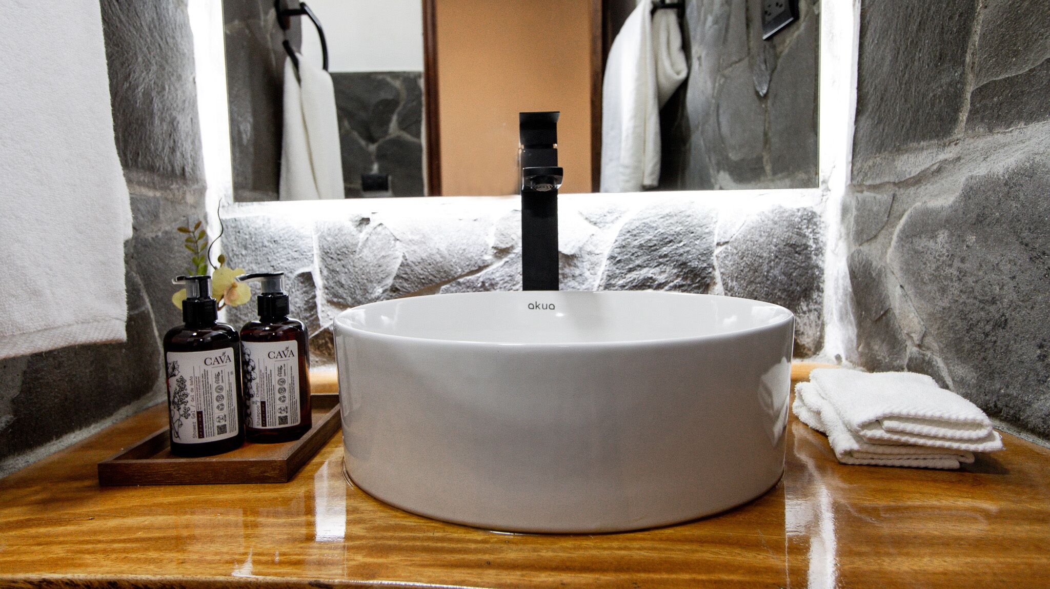 Un bagno con un lavandino bianco tondo, uno specchio e un porta asciugamani.
