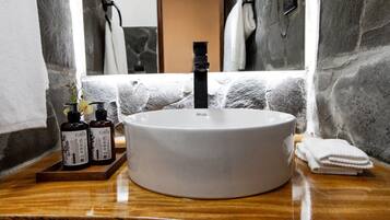 Un bagno con un lavandino bianco tondo, uno specchio e un porta asciugamani.