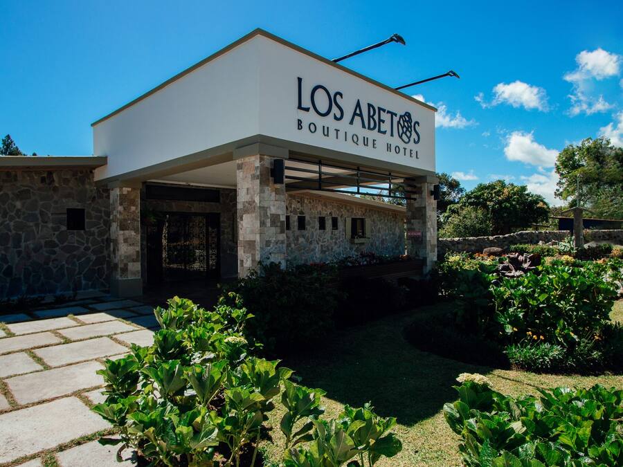 A boutique hotel with a stone facade and a clear blue sky.