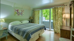 A bedroom with a bed, a nightstand, a lamp, a dresser, and a window with curtains. - Mercer House in Hocking Hills (Sugar Grove)