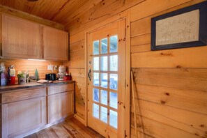 L’intérieur d’une cabane en bois comprend un espace cuisine, une porte avec une fenêtre et une pancarte de bienvenue.