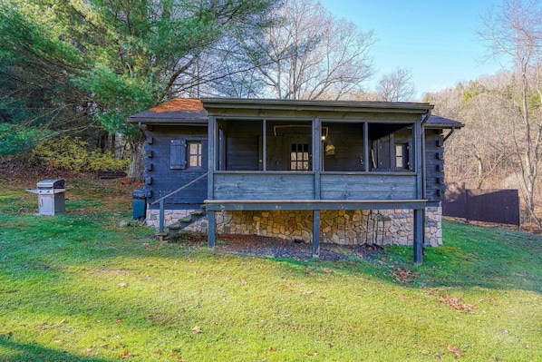 Une cabane rustique avec des fondations en pierre, un revêtement extérieur en bois et une véranda dotée d’un banc.