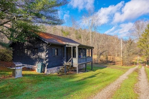 Un chalet rustique doté d’une véranda, d’un barbecue et d’un sentier menant à l’entrée.