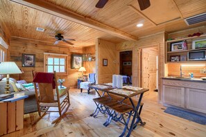 Ein gemütliches Holzhaus-Interieur mit Esstisch, Schaukelstuhl und Küchenbereich.