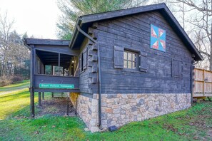 A rustic wooden cabin with a stone foundation, a covered porch, and a sign indicating it is Bison Hollow Hideaway. - Bison Hollow Hideaway (South Bloomingville)