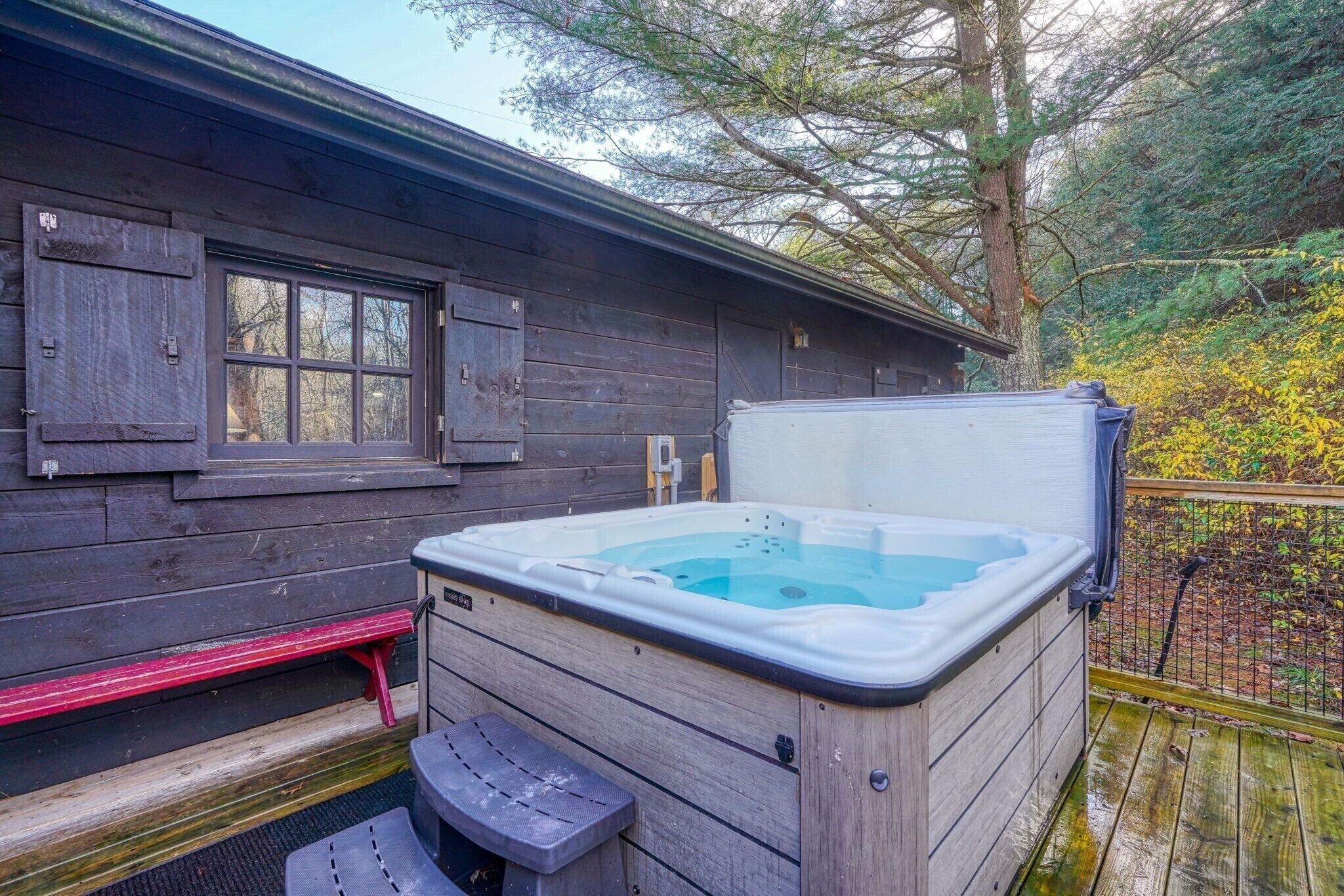 A wooden cabin with a hot tub and a bench.