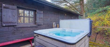 A wooden cabin with a hot tub and a bench.