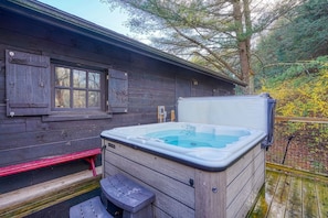 Eine Holzhütte mit Whirlpool und Bank.