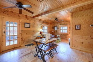 Ein Holzhäuschen im Inneren mit einem Esstisch, Bänken, Deckenventilatoren und gerahmten Bildern an den Wänden.