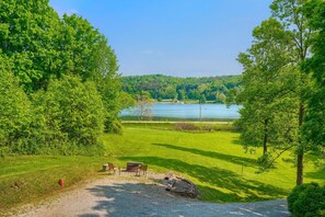 A grassy area with a gravel path leading to a picnic setup with a table and chairs. - Lakewood Cottage in Hocking Hills (Logan)