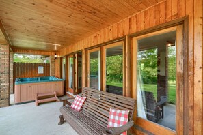 A wooden cabin with a hot tub, a bench, and a view of the outdoors.