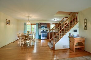 A spacious kitchen with wooden cabinets, a microwave, stove, and a wooden staircase leading to an upper level. - Lakewood Cottage in Hocking Hills (Logan)