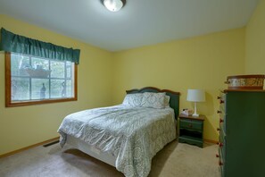 A bedroom with a bed, a nightstand, a lamp, and a dresser.