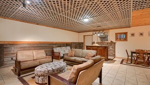 A cozy living room with a wooden ceiling, a fireplace, and a dining area with wooden furniture.