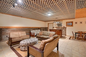 A cozy living room with a wooden ceiling, a fireplace, and a dining area with wooden furniture. - Lakewood Cottage in Hocking Hills (Logan)