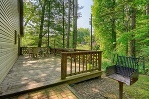 A wooden deck with outdoor furniture, surrounded by trees.