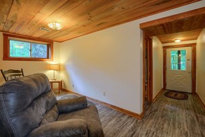Ein Zimmer mit Ledersofa, Holzboden und einer Tür zu einem weiteren Raum.