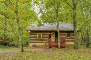 A rustic cabin with a wooden deck and a mailbox.