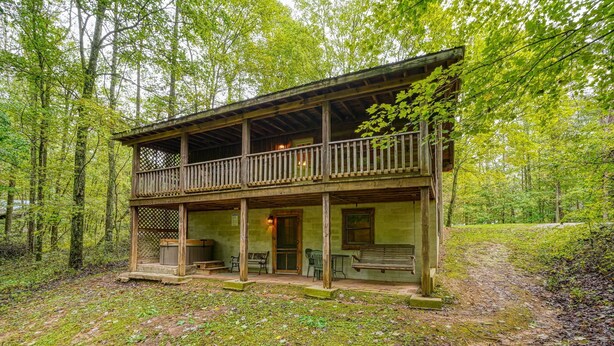 A rustic cabin with a balcony, wooden deck, and a porch area with seating. - Chickasaw in Hocking Hills (Logan)