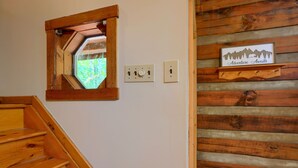 A wooden staircase with a wooden-framed window and a wall-mounted sign that reads "Adventure Awaits". - Cherokee in Hocking Hills (Logan)