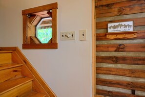 A wooden staircase with a wooden-framed window and a wall-mounted sign that reads "Adventure Awaits".