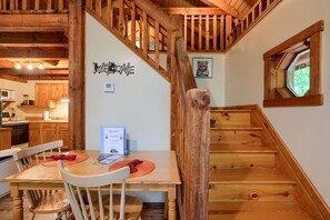 Un escalier en bois avec une rampe en bois, une table à manger avec des chaises et un coin cuisine avec des placards en bois.