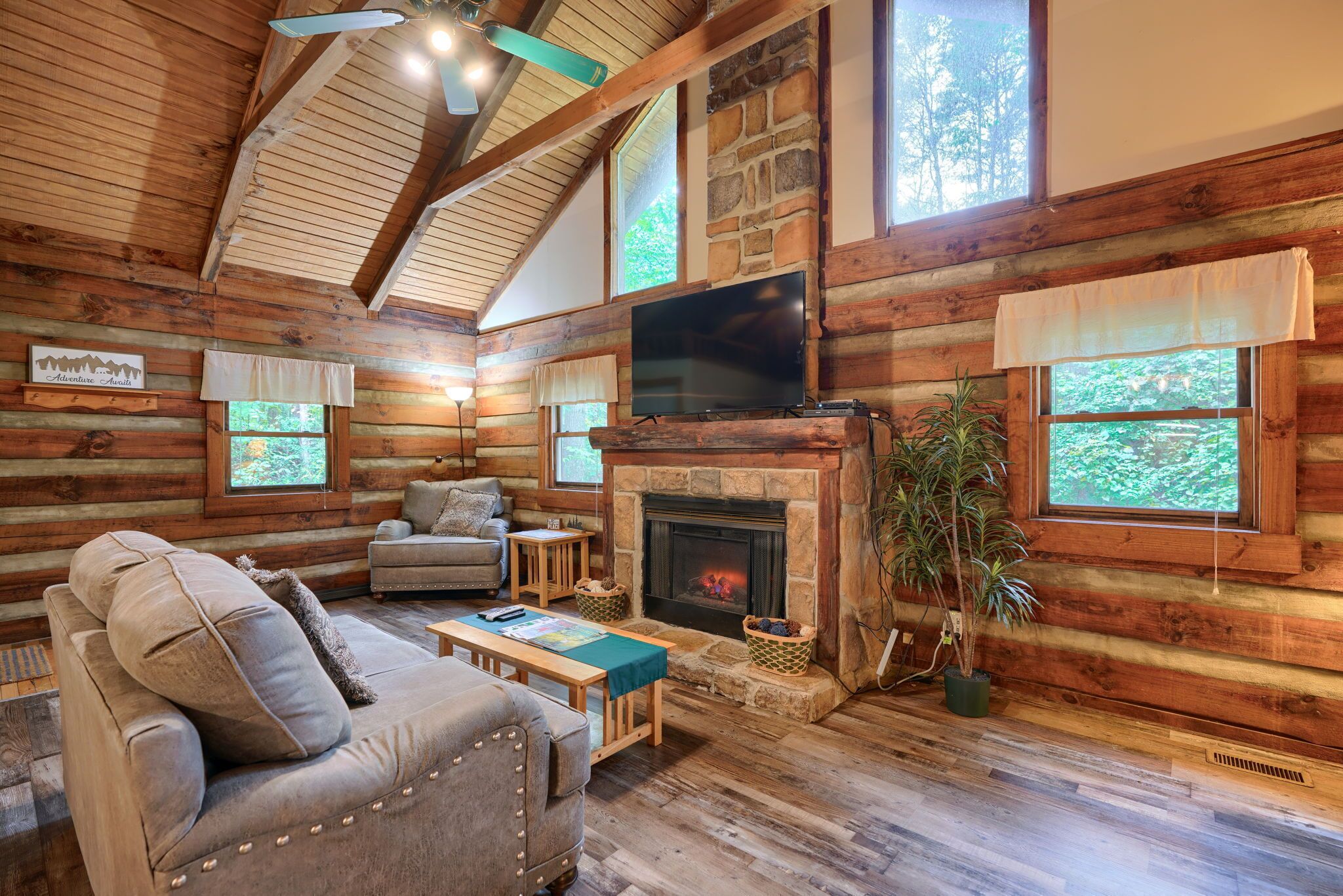 L’intérieur d’un chalet confortable, avec une cheminée, des murs en bois et un téléviseur.