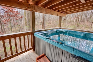 Un bain à remous sur une terrasse en bois, avec vue sur une forêt.