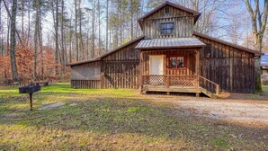 A rustic wooden cabin with a porch, surrounded by a forest. - Navajo in Hocking Hills (Logan)