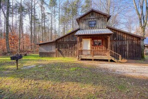 A rustic wooden cabin with a porch, surrounded by a forest. - Navajo in Hocking Hills (Logan)