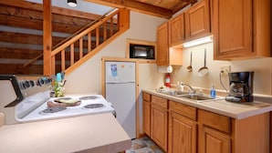 A kitchen with wooden cabinets, a white stove, a microwave, and a coffee maker. - Navajo in Hocking Hills (Logan)