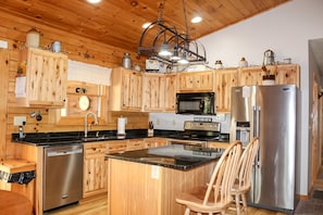 A kitchen with wooden cabinets, a stainless steel refrigerator, a microwave, and a sink.