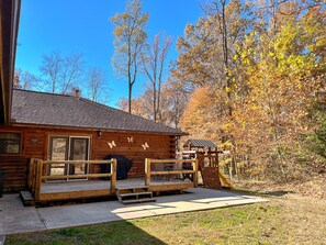 A wooden cabin with a deck, a covered outdoor seating area, and a rock climbing wall. - Dewdrop Inn in Hocking Hills (Logan)